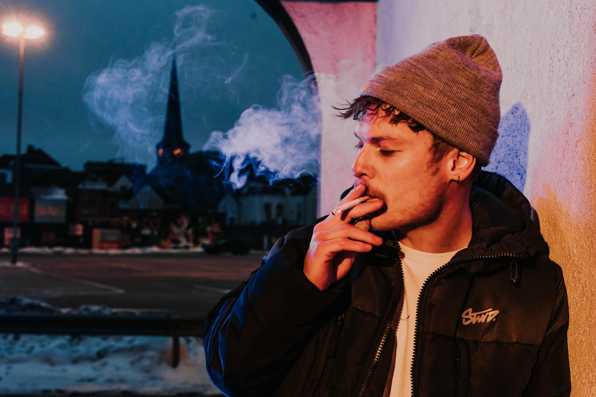 Rokende man met muts in portiek in de avond in Breda